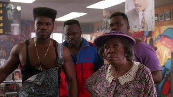 Movie still from “House Party 2” (1991), directed by Doug McHenry – A group of men and women standing next to each other in a room; Medium shot, Low angle