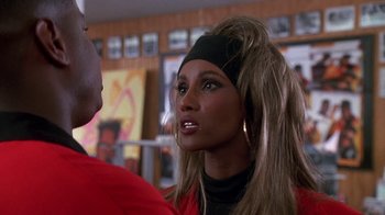 Movie still from “House Party 2” (1991), directed by Doug McHenry – A person wearing a wig and looking at the camera; Close Up shot, Over the shoulder angle