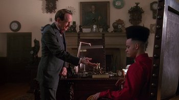 Movie still from “House Party 2” (1991), directed by Doug McHenry – A man in a suit and tie standing next to a man in a red shirt; Medium shot, Over the shoulder angle