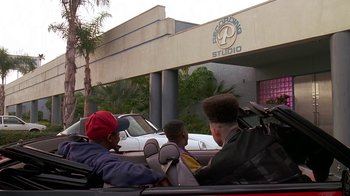 Movie still from “House Party 2” (1991), directed by Doug McHenry – Three people in a car in front of a building; Wide shot, Low angle