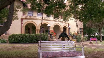 Movie still from “House Party 2” (1991), directed by Doug McHenry – A person is sitting on a bench in front of a building; Extreme Wide shot, Low angle