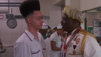 Movie still from “House Party 2” (1991), directed by Doug McHenry – Two young men are standing in front of a group of people; Close Up shot, Over the shoulder angle
