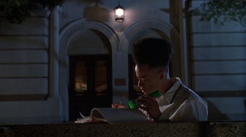 Movie still from “House Party 2” (1991), directed by Doug McHenry – A person sitting in front of an open book at night; Medium shot, Low angle