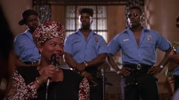 Movie still from “House Party 2” (1991), directed by Doug McHenry – A group of men and a woman standing next to each other; Medium shot, Low angle