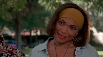 Movie still from “House Party 2” (1991), directed by Doug McHenry – A woman with a headband smiles for the camera; Close Up shot, Over the shoulder angle