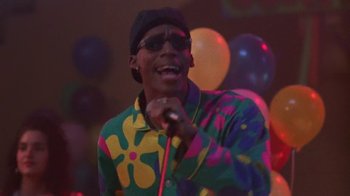 Movie still from “House Party 2” (1991), directed by Doug McHenry – A man in a multicolored shirt is holding a microphone; Medium shot, Low angle