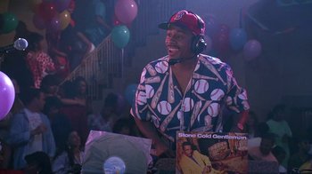 Movie still from “House Party 2” (1991), directed by Doug McHenry – A man wearing a baseball cap and headphones is standing in front of some records; Medium shot, High angle