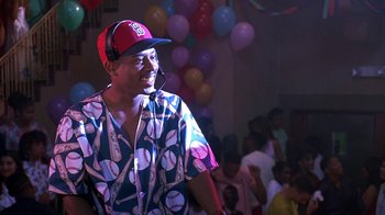 Movie still from “House Party 2” (1991), directed by Doug McHenry – A man wearing a baseball hat and a shirt; Medium shot, Over the shoulder angle