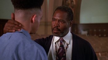 Movie still from “House Party 2” (1991), directed by Doug McHenry – A man wearing a suit and tie talking to another man in front of a wall; Close Up shot, Over the shoulder angle