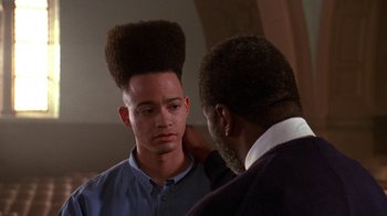 Movie still from “House Party 2” (1991), directed by Doug McHenry – A man with an afro is being shaved by another man; Close Up shot, Low angle