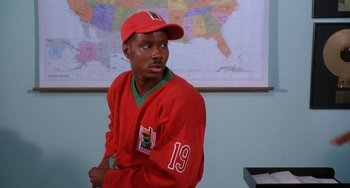 Movie still from “House Party 3” (1994), directed by Eric Meza – A man in a red shirt and a red hat is in front of a map; Close Up shot, High angle