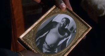 Movie still from “House Party 3” (1994), directed by Eric Meza – A person holding a picture of a man in a tank top; Extreme Close Up shot, High angle