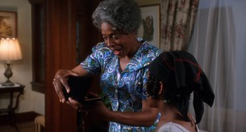Movie still from “House Party 3” (1994), directed by Eric Meza – An older woman cutting a young girl's hair with scissors; Medium shot, Over the shoulder angle