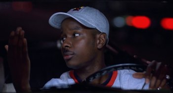 Movie still from “House Party 3” (1994), directed by Eric Meza – A young man wearing a baseball cap while holding a tennis racquet; Close Up shot, Low angle