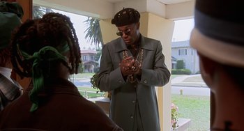Movie still from “House Party 3” (1994), directed by Eric Meza – A man wearing a hat and a jacket holding a chain; Medium shot, Over the shoulder angle