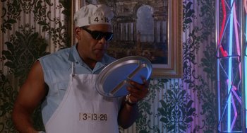 Movie still from “House Party 3” (1994), directed by Eric Meza – A man wearing an apron holding a metal pan; Medium shot, Low angle