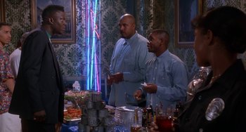 Movie still from “House Party 3” (1994), directed by Eric Meza – A group of men standing around a table with food; Medium shot, Over the shoulder angle