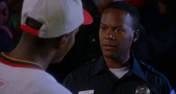 Movie still from “House Party 3” (1994), directed by Eric Meza – A man wearing a hat and a uniform talking to another man; Close Up shot, Over the shoulder angle