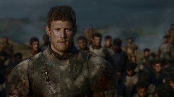 Movie still from “Game of Thrones” (2011), created by D.B. Weiss – A group of people standing around a man wearing a suit of armor; Close Up shot, Low angle