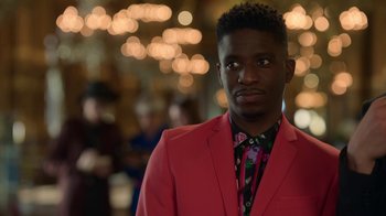 Movie still from “Emily in Paris” (2020), created by Darren Star – A man in a red suit standing in front of lights; Close Up shot, Over the shoulder angle