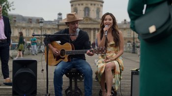 Movie still from “Emily in Paris” (2020), created by Darren Star – A man and a woman singing and playing a guitar; Medium shot, High angle