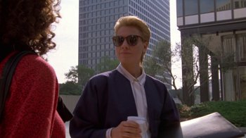 Movie still from “House of Games” (1987), directed by David Mamet – A woman in sunglasses holding a cup of coffee; Medium shot, Low angle