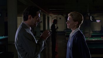 Movie still from “House of Games” (1987), directed by David Mamet – A man and a woman are talking in a dark room; Medium shot, Over the shoulder angle