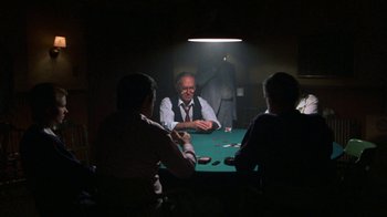 Movie still from “House of Games” (1987), directed by David Mamet – A group of people sitting at a table playing poker; Wide shot, Over the shoulder angle