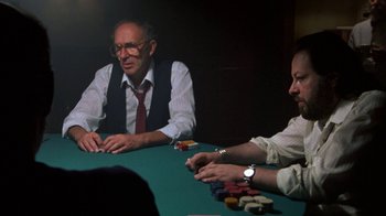 Movie still from “House of Games” (1987), directed by David Mamet – Two men sitting at a green table playing poker; Medium shot, Over the shoulder angle