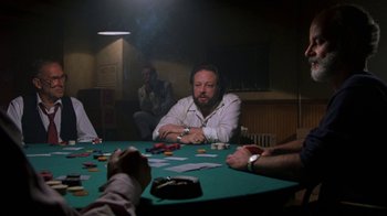 Movie still from “House of Games” (1987), directed by David Mamet – A man sitting at a table with a lot of cards; Medium shot, Over the shoulder angle