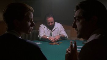 Movie still from “House of Games” (1987), directed by David Mamet – A group of men sitting around a table playing cards; Medium shot, Over the shoulder angle