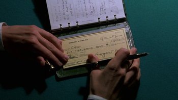 Movie still from “House of Games” (1987), directed by David Mamet – A person writing a check on top of a green table; Extreme Close Up shot, Overhead angle