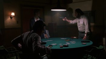 Movie still from “House of Games” (1987), directed by David Mamet – A group of people sitting around a table with cards; Medium shot, Over the shoulder angle