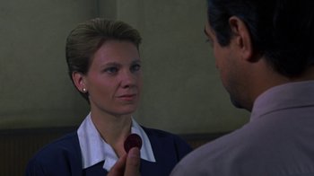 Movie still from “House of Games” (1987), directed by David Mamet – A woman holding a red object in front of a man; Close Up shot, Over the shoulder angle