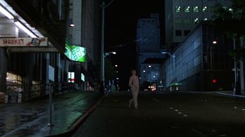 Movie still from “House of Games” (1987), directed by David Mamet – A person walking down a street at night; Wide shot, Low angle