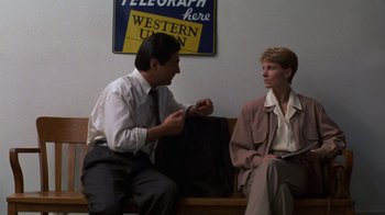 Movie still from “House of Games” (1987), directed by David Mamet – A man and a woman are sitting on a bench; Medium shot, Low angle