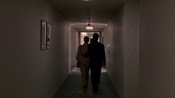 Movie still from “House of Games” (1987), directed by David Mamet – A man and a woman are walking down a hallway; Wide shot, Low angle