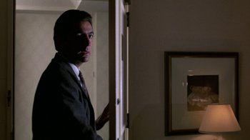 Movie still from “House of Games” (1987), directed by David Mamet – A man in a suit standing in front of an open door; Medium shot, Over the shoulder angle