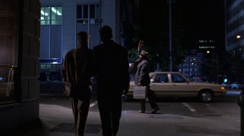 Movie still from “House of Games” (1987), directed by David Mamet – Two people walking down a street at night; Wide shot, Over the shoulder angle