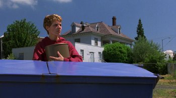 Movie still from “House of Games” (1987), directed by David Mamet – A man holding a pan standing next to a dumpster; Medium shot, Low angle