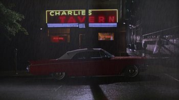 Movie still from “House of Games” (1987), directed by David Mamet – A car parked on the side of the road in front of a restaurant; Extreme Wide shot, High angle