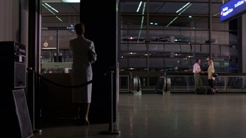 Movie still from “House of Games” (1987), directed by David Mamet – A woman in a white dress standing in front of a window; Wide shot, Low angle