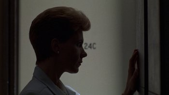 Movie still from “House of Games” (1987), directed by David Mamet – A woman with short blonde hair looking into a mirror; Close Up shot, Low angle