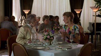 Movie still from “House of Games” (1987), directed by David Mamet – A group of people sitting around a table; Medium shot, Over the shoulder angle