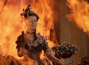 Movie still from “House of Wax” (1953), directed by André De Toth – A statue of a woman is burning in a fireplace; Medium shot, High angle