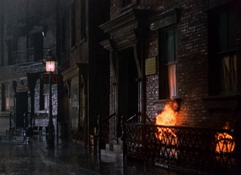 Movie still from “House of Wax” (1953), directed by André De Toth – A fire is burning on the side of a building; Extreme Wide shot, High angle
