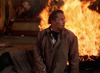 Movie still from “House of Wax” (1953), directed by André De Toth – A man standing in front of a burning fire; Medium shot, Over the shoulder angle