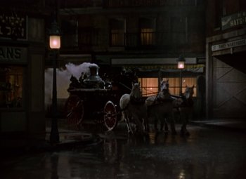 Movie still from “House of Wax” (1953), directed by André De Toth – Two horses pulling a carriage down the street at night; Wide shot, High angle