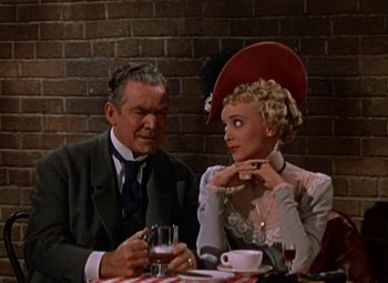 Movie still from “House of Wax” (1953), directed by André De Toth – An older man sitting next to an older woman at a table; Medium shot, Low angle