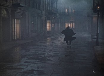 Movie still from “House of Wax” (1953), directed by André De Toth – A person walking down a street in the rain; Wide shot, High angle